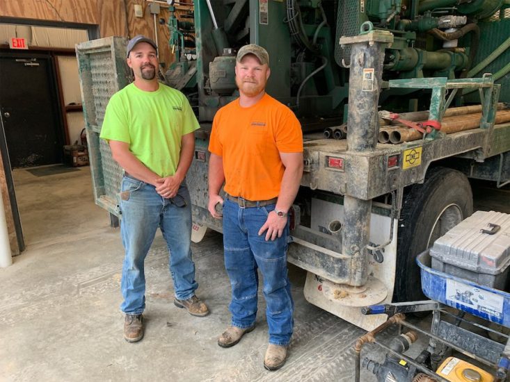 Two men standing next to machinery