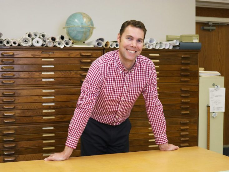 Man in red gingham shirt leaning on table