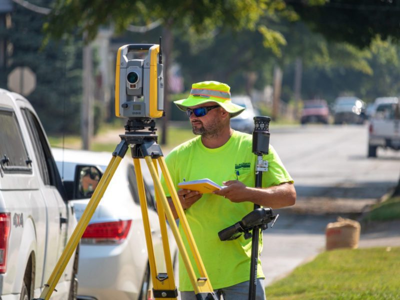 A surveyor surveying next to a roadway