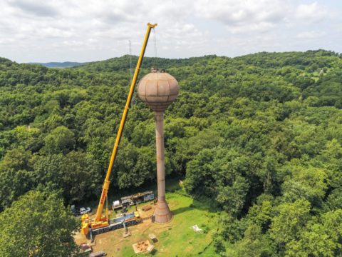 The bowl of a water tower being lifted into place by a crane