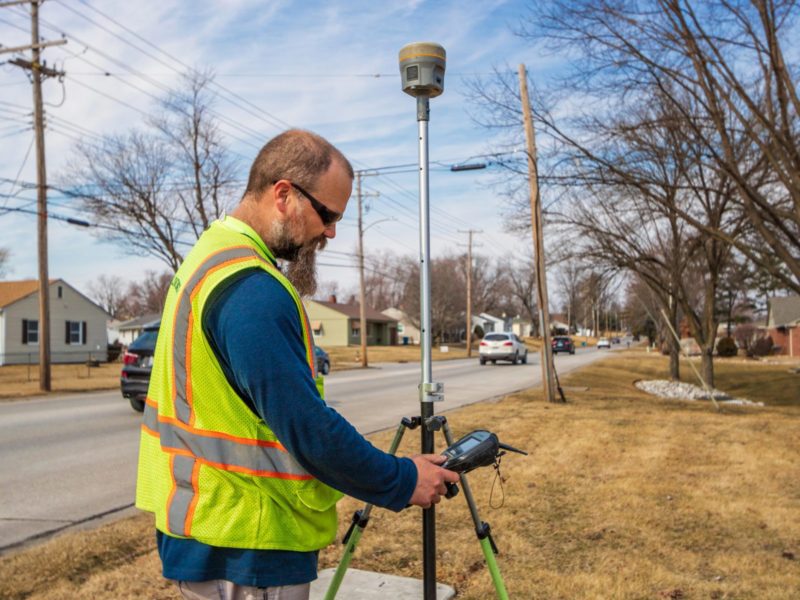 A man surveying in a yard next to a roadway