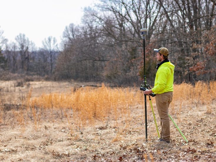 A man surveying near the woods