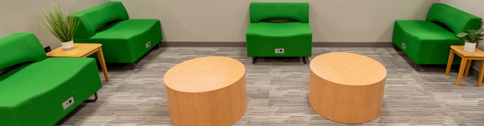 Green chairs and light wooden tables in a waiting area