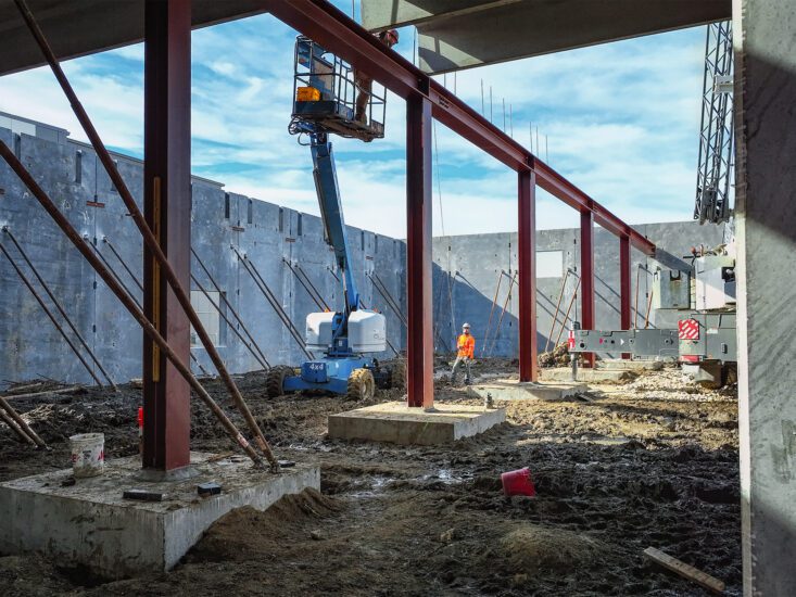 Structural columns standing in the middle of a construction site with a worker looking up