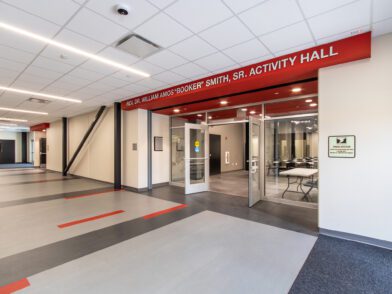 The entrance of the multipurpose room, featuring a glass storefront and red sign that says Rev. Dr. William Amos "Booker" Smith, Sr. Activity Hall