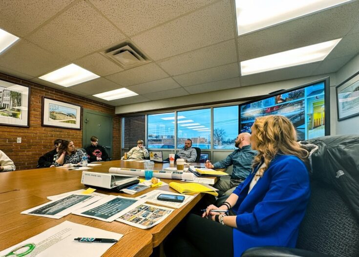 A group of people sitting around a table with design documents in front of them
